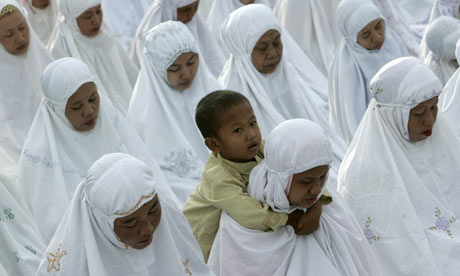 A woman carries a child on her shoulders as Muslims pray to celebrate Eid al-Adha in Jakarta, Indonesia. Photograph: Supri/Reuters